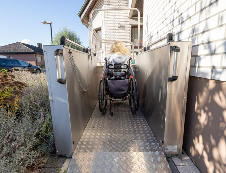Rollstuhlfahrerin steht mit Rollstuhl auf einem Hublift